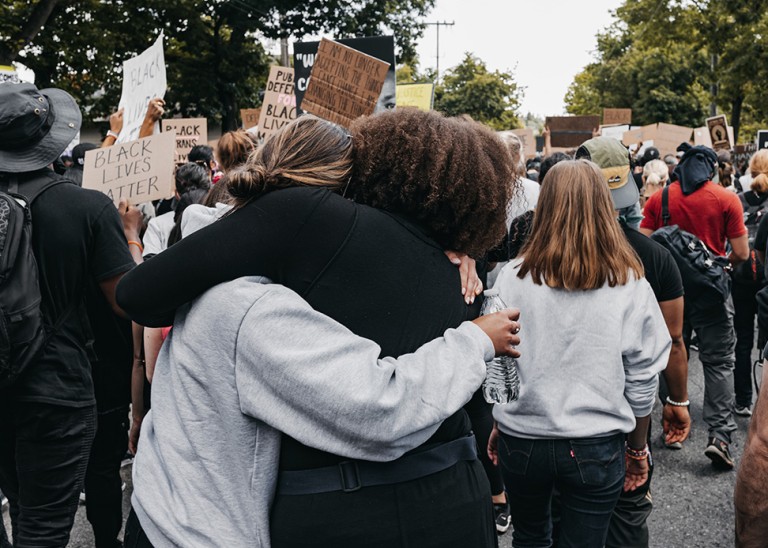 Two women in a crowd embrace as they demonstrate for racial justice, Seattle, USA, 10 June 2020. © Duncan Shaffer/UNSPLASH