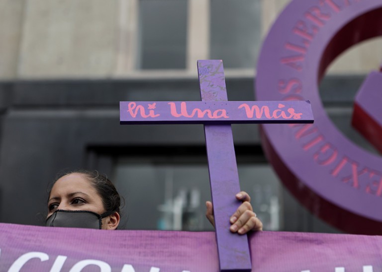 A woman holds a cross reading "no more missing" during a march demanding justice for the victims of gender violence and femicides in Mexico City, Mexico. © REUTERS/Raquel Cunha. 